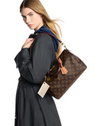 MOAH Louis Vuitton Speedy handbag in monogram canvas with burgundy leather trim worn over the shoulder by a model.