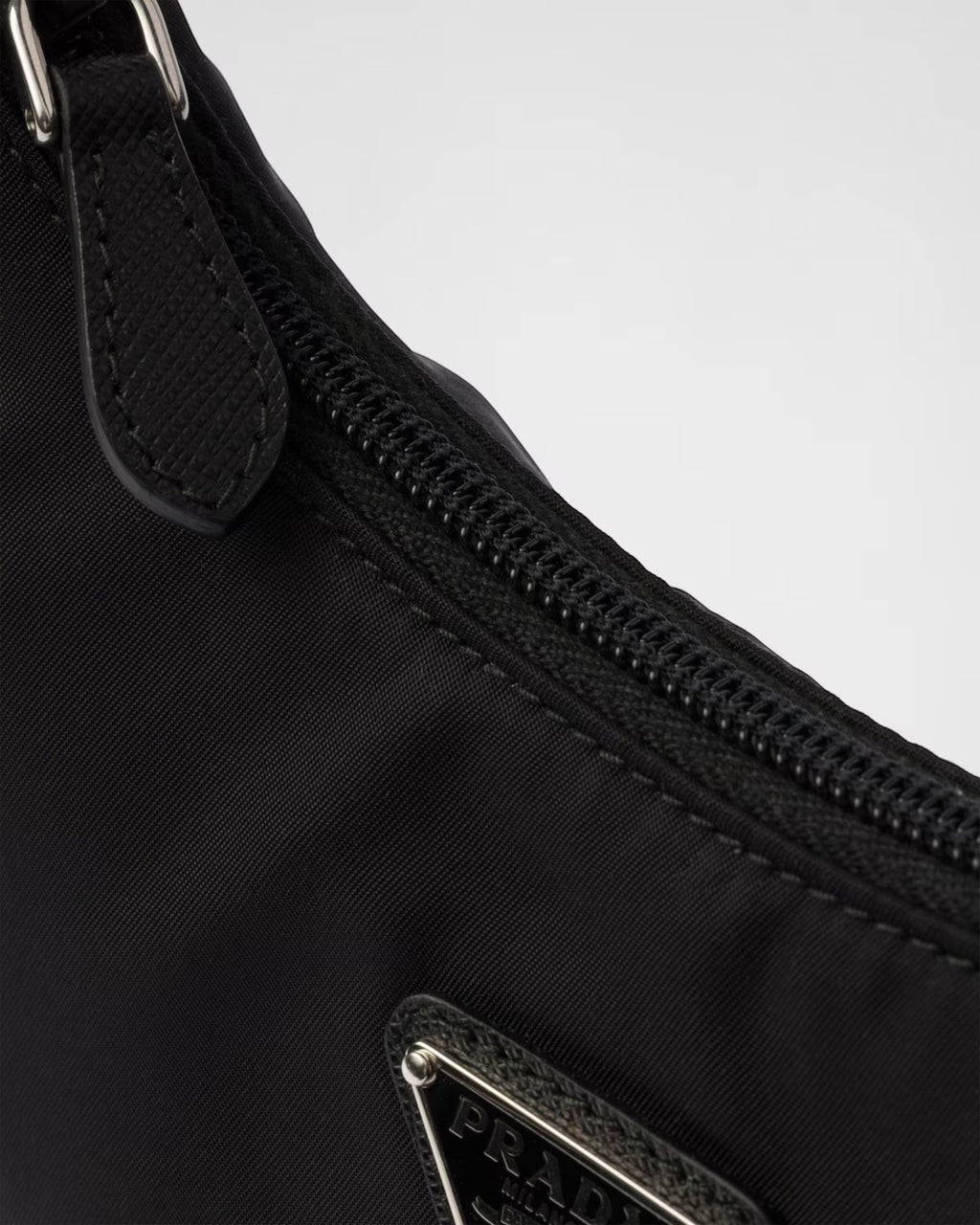 MOAH Prada Re-Edition 2000 mini bag in black Re-Nylon featuring a zip closure and enameled metal triangle logo detail.