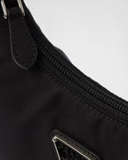 MOAH Prada Re-Edition 2000 mini bag in black Re-Nylon featuring a zip closure and enameled metal triangle logo detail.