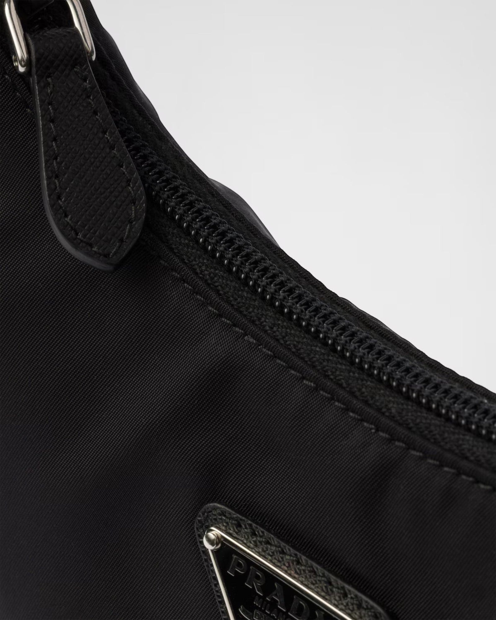 MOAH Prada Re-Edition 2000 mini bag in black Re-Nylon featuring a zip closure and enameled metal triangle logo detail.