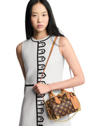 Model carrying the Louis Vuitton Speedy Trunk 20 in monogram canvas with gold chain and leather trim.